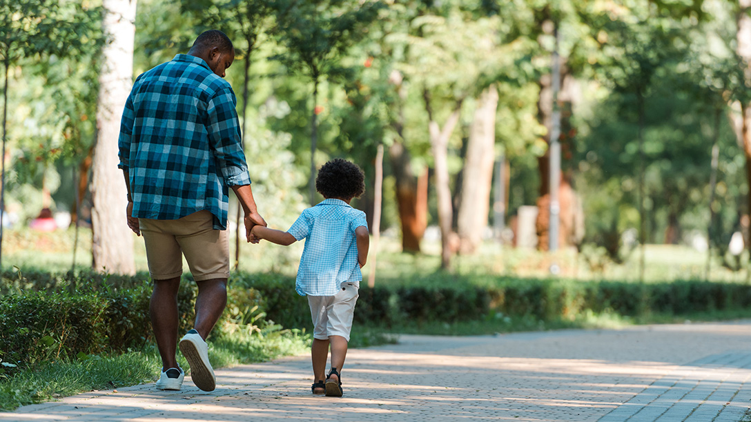 Father and son walking down a path at park