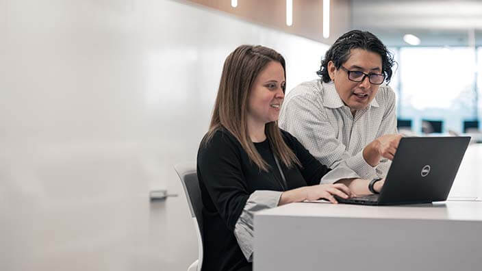 Male and female Oxy employee looking at laptop